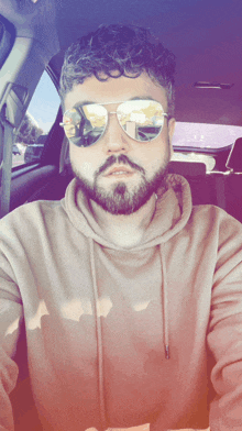 a man with a beard wearing sunglasses and a tan hoodie