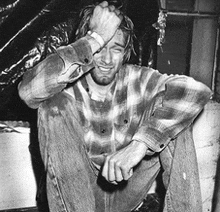 a man in a plaid shirt is kneeling down with his hands on his head