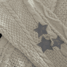 a close up of a white sweater with three stars on the sleeves .