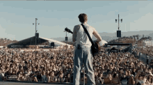 a man playing a guitar in front of a crowd at a music festival with the word cancelled in the corner