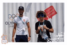 a man and a woman are posing for a photo in front of a sign that says youth olympic games