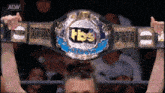 a woman holds up a tbs championship belt over her head