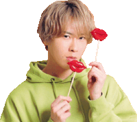 a young man in a green hoodie is holding two red lips on a stick