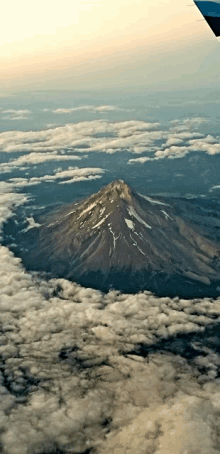 an aerial view of a mountain covered in snow and clouds