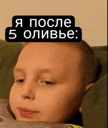 a young boy laying on a couch with a sticker on his head that says " я после 5 оливье "