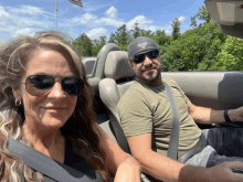 a man and a woman wearing sunglasses are sitting in a convertible car