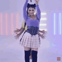 a woman in a purple top and plaid skirt is dancing