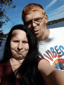 a man and a woman are posing for a picture and the man is wearing a vibes shirt