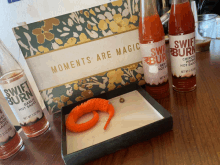 a bottle of swift burn garlic hot sauce sits on a table next to a card that says moments are magic