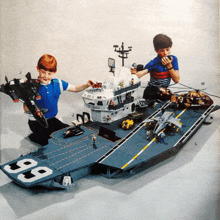 two young boys are playing with a toy aircraft carrier with the number 88 on it