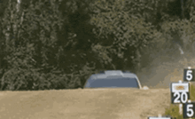 a car is driving down a dirt road with a sign that says 20 on it .
