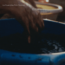 a person washing their hands in a blue tub with la guarimba film festival written on the bottom of the image