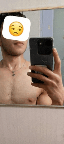 a shirtless man is taking a selfie in front of a mirror with a sad face on his face .