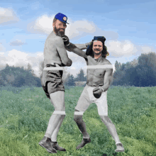 two men are boxing in a field and one has a blue hat on