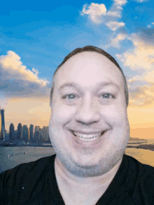 a man is smiling in front of a city skyline at sunset