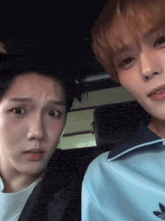 two young men are sitting next to each other in a car and one of them is wearing a blue adidas jacket .