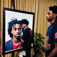 a man stands in front of a framed picture of a man wearing a shirt that says chicago bulls