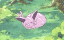 a pink rabbit is laying in the grass .