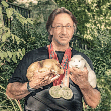 a man holding two guinea pigs wearing a lanyard that says " ham "