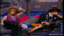 a man is playing a guitar next to a woman on a couch