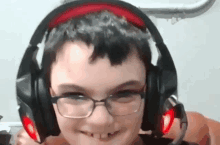 a young boy wearing glasses and headphones is smiling for the camera .