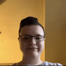 a boy wearing glasses and a white shirt smiles for the camera