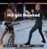 a man in a suit is standing next to a shirtless man in a boxing ring with the caption hill got hawked .