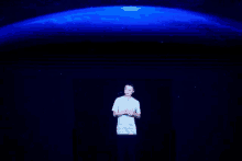 a man in a white shirt is standing in front of a projection of the earth .