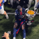 a soccer player in a qatar jersey holds a trophy on the field