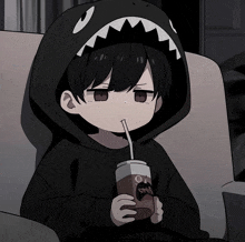 a boy wearing a shark hoodie drinks from a cup with a straw