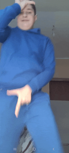 a man in a blue sweatshirt is pointing at his pants