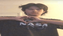 a man wearing a nasa shirt makes a heart with his hands