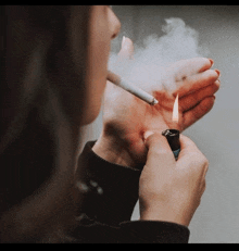 a woman is lighting a cigarette with a lighter that has the letter t on it