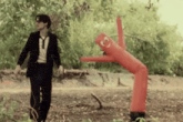 a man in a suit and tie is walking next to a red inflatable man
