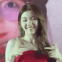 a woman in a red dress is smiling in front of a large screen