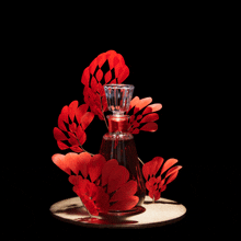 a bottle of perfume is decorated with red flowers and leaves