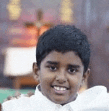 a young boy in a white shirt is smiling in front of a cross in a church .