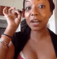 a woman is applying mascara to her eyelashes and making a face .