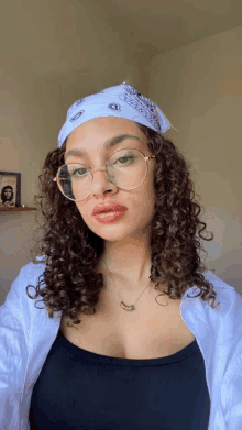 a woman wearing glasses and a bandana has a picture of che guevara on the shelf behind her