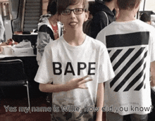 a boy wearing a bape t-shirt stands in a crowd of people