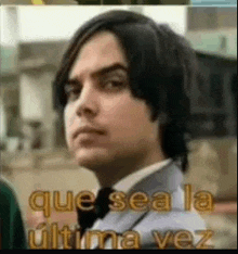 a man in a tuxedo and bow tie is standing in front of a sign that says que sea la ultima vez .