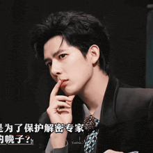 a man in a suit and tie is holding his finger to his mouth