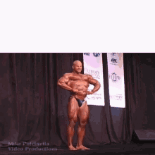 a bodybuilder is flexing his muscles on a stage in front of a sign that says " the future "