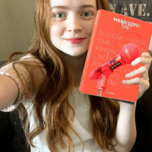 a girl is holding a red book that says manifesto on it