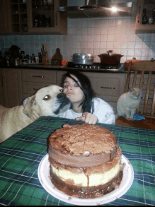 a woman kisses a dog on the cheek while a cat sits behind her