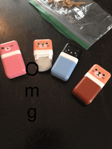 four erasers are on a table with the letters o m and g below them