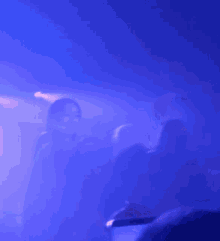 a blurry picture of a person standing on a stage with a blue light behind them