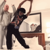 two people are dancing on a bed in front of a mirror and a mirrored wall