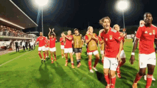 a group of soccer players are walking on a field and one of them is wearing a jersey that says benfica