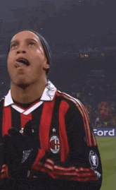 a soccer player wearing a red and black striped adidas jersey